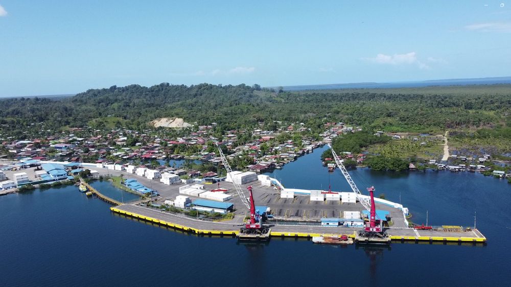 Muelle de frente opaco con grúas portuarias operando en un terminal