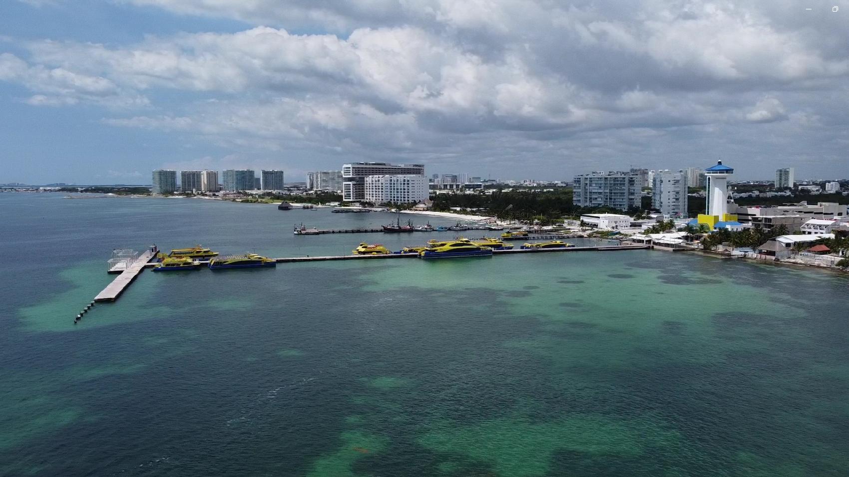 Muelle sobre aguas turquesas junto a un frente urbano costero